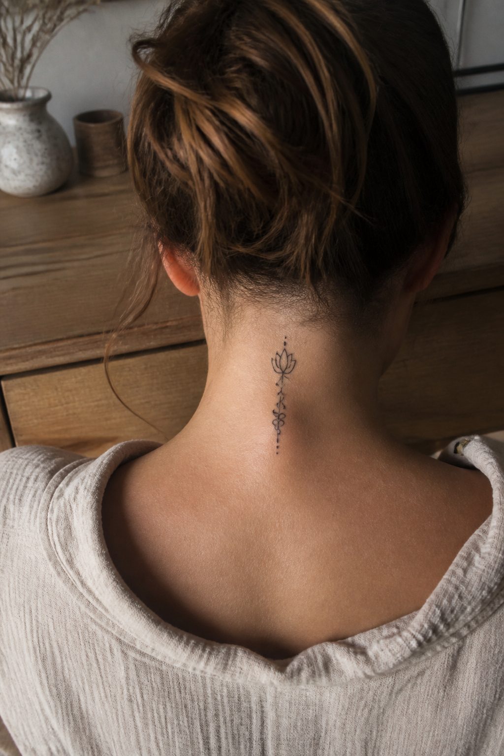 Close-up of a dainty back-of-the-neck tattoo featuring fine linework.