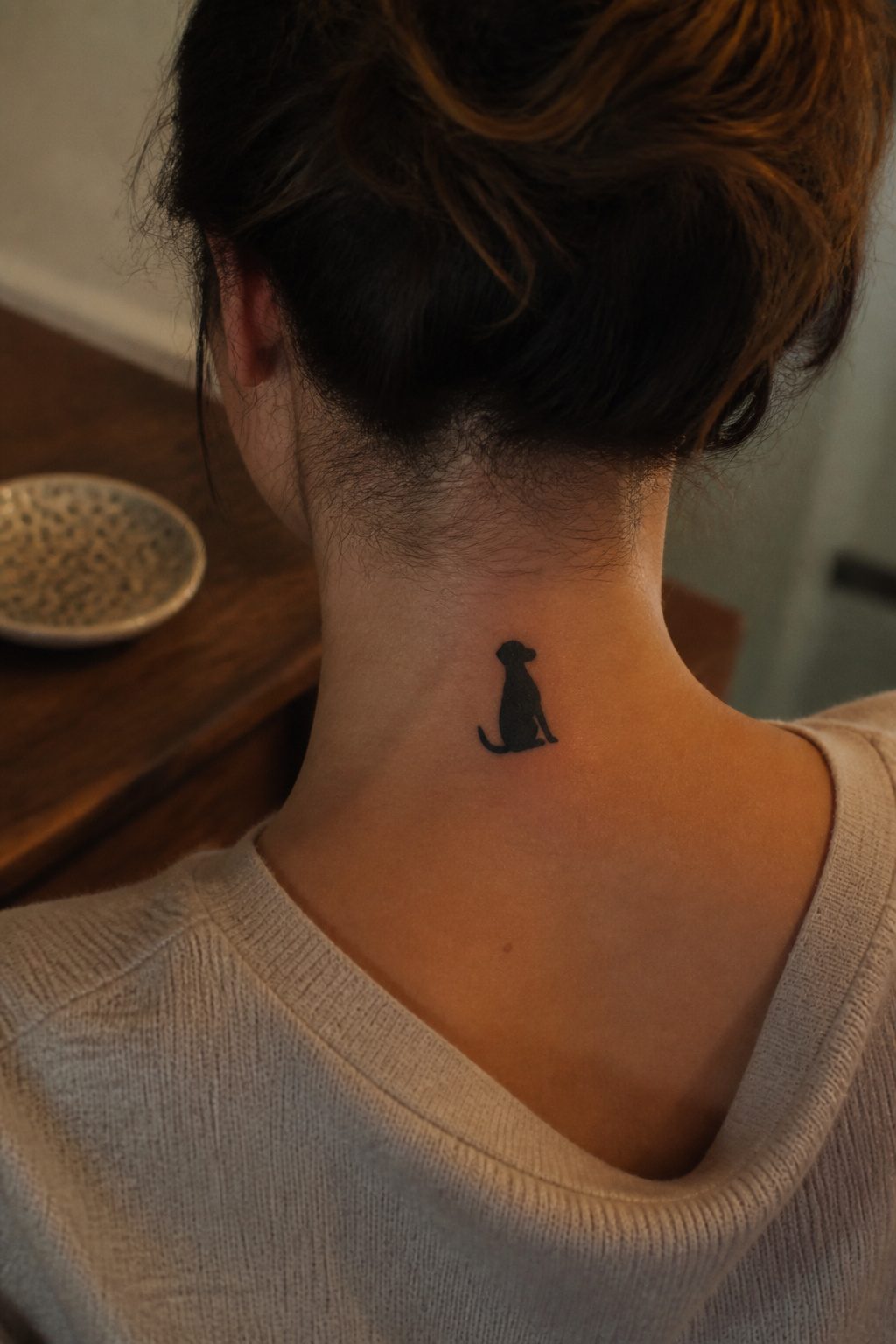 Tattoo of a dog portrait located at the back of the neck.