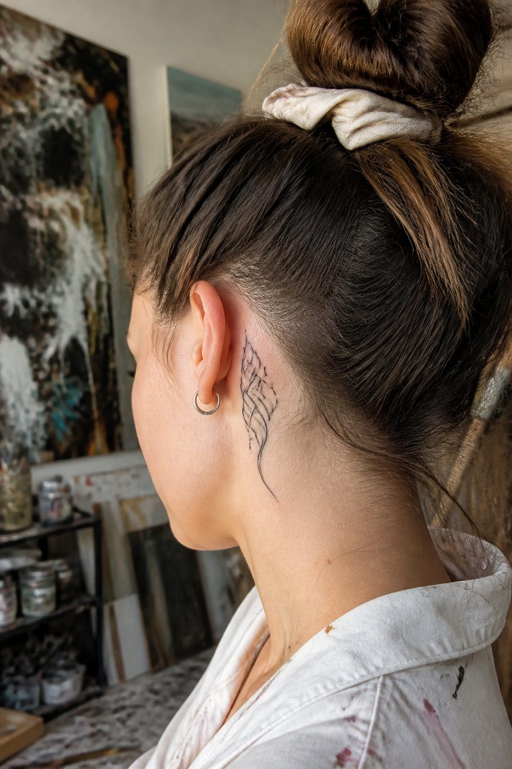 Black abstract brush stroke tattoo behind a model's ear.