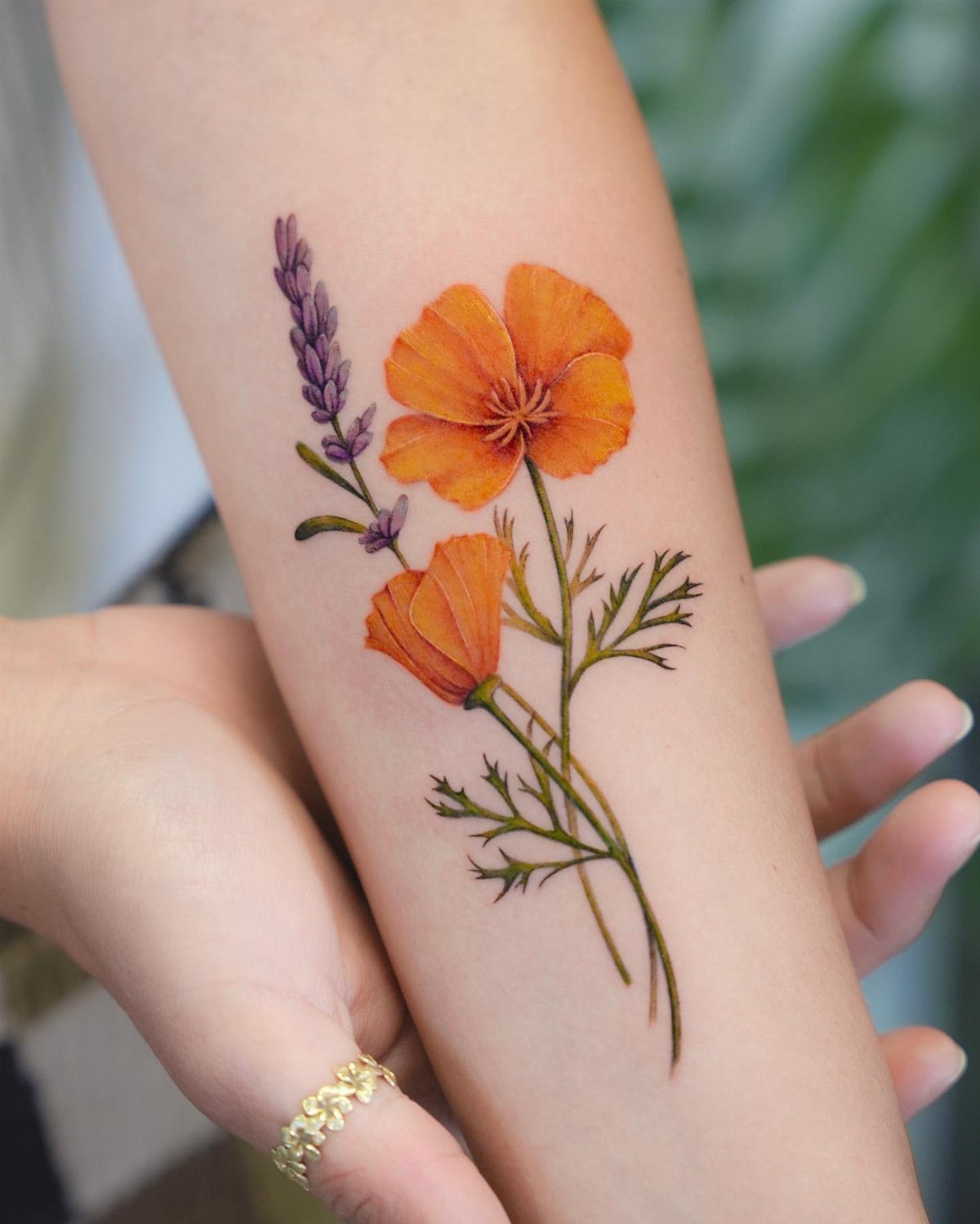 17 Flower Tattoo Ideas That Work in Every Style 17 Orange poppy and purple lavender floral tattoo on a person's forearm.