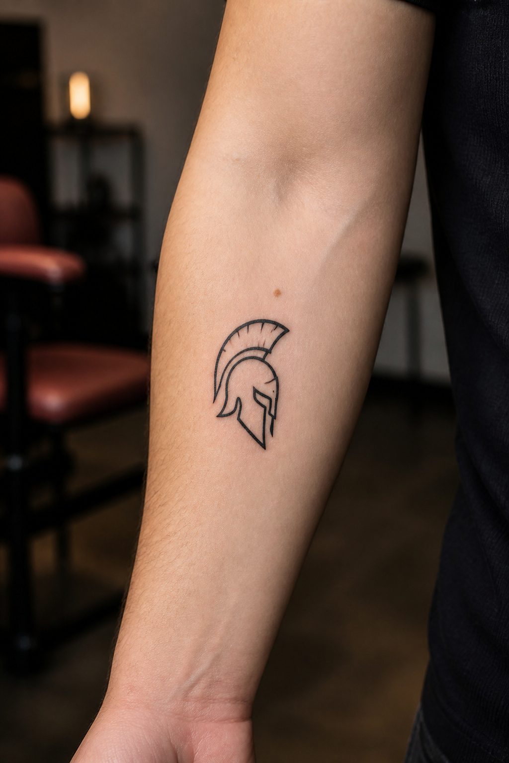 A simple Spartan helmet tattoo on a client's inner forearm.